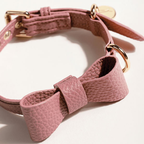 Smukt og feminint hundehalsbånd i lyserød lavet i vegansk læder med fin aftagelig sløjfe og guld detaljer. Hundetegn i guld uden indgravering.